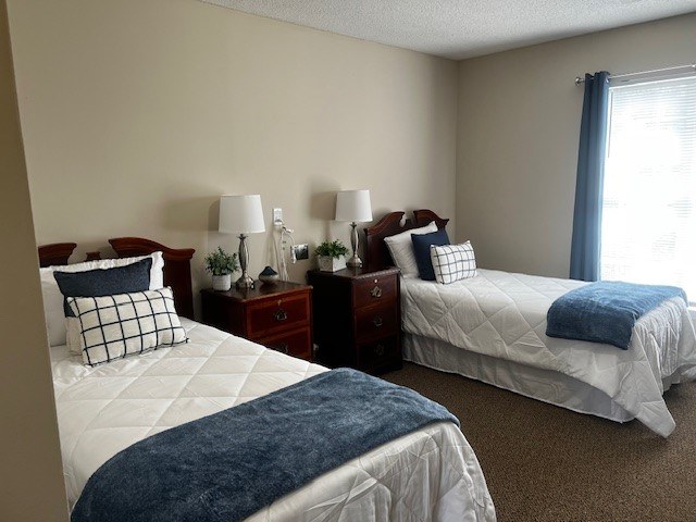 Two twin beds with blue blankets in a room with two nightstands at Spring Arbor of Rocky Mount